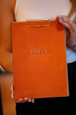 Orangefarbene Speisekarte mit AURO-Logo im Restaurant AURO Langen