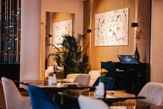 Heller Gastraum mit Samtstühlen, Holzlamellen und abstrakter Kunst im Restaurant AURO Langen